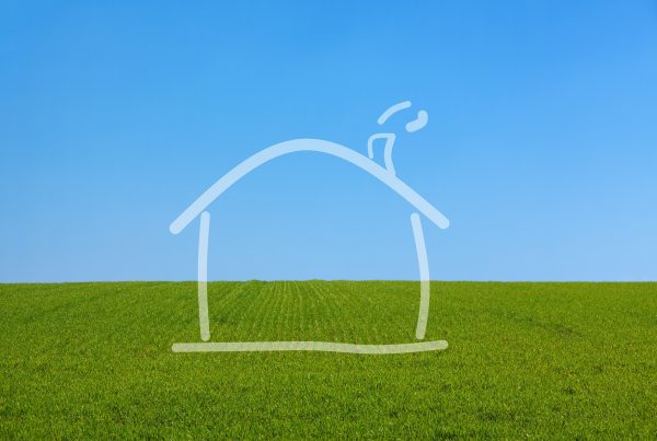 Outline of a house on a background of green grass and blue sky