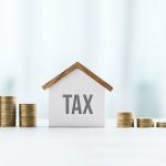 House model and stack of coins representing property, values, and real estate taxes