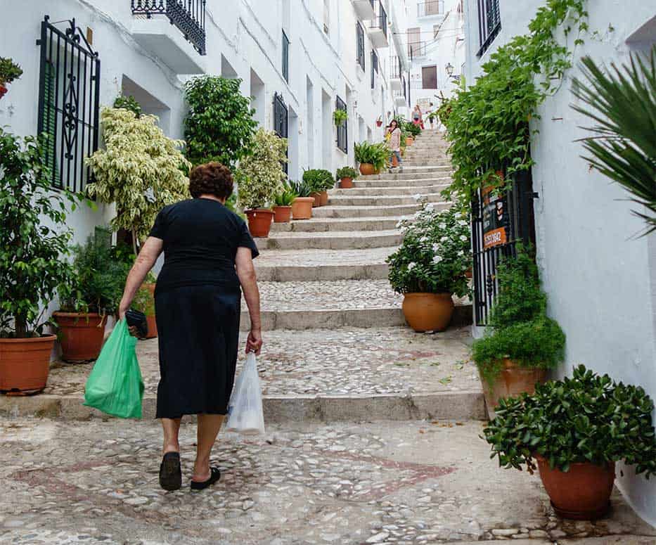 An elderly woman in a spanish pueblo walking home 