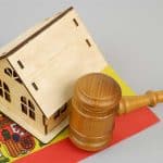 Spanish Markets Report – Aug 2026 Part 2 - Legal Changes & Regulatory Influences Law and real estate business in Spain. Judge gavel with wooden house model and Spanish flag on gray background.