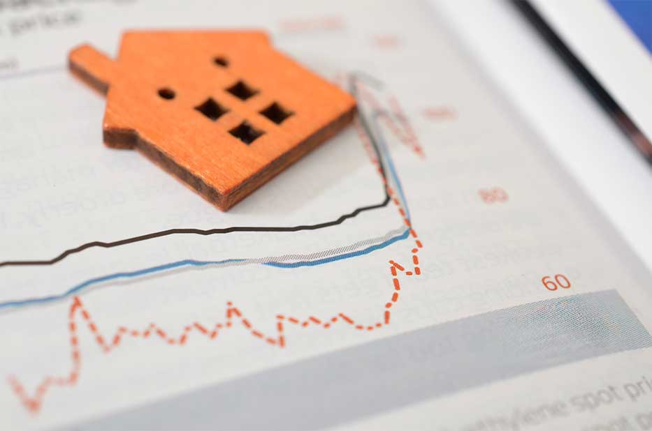 Property investment and housing market analysis showing wooden home model on data graph.