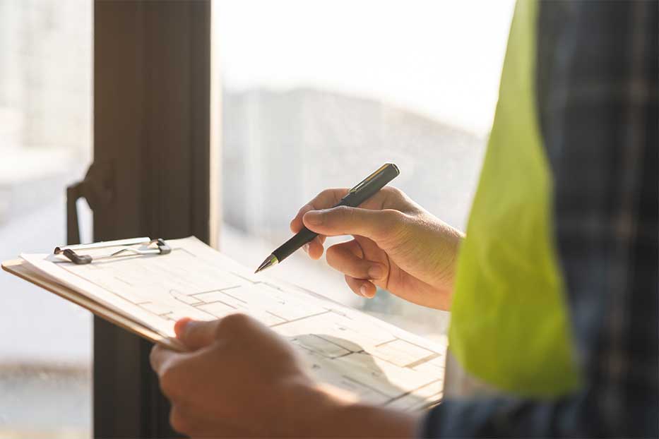 Professional home inspector wearing a safety vest and holding a clipboard with a home inspection report 